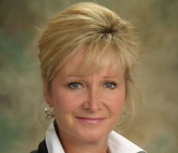 A Woman Wearing Glasses And Smiling At The Camera