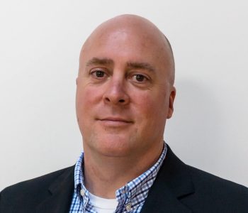 A Man Wearing A Suit And Tie Smiling At The Camera
