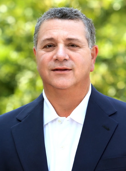 a man wearing a suit and tie smiling at the camera