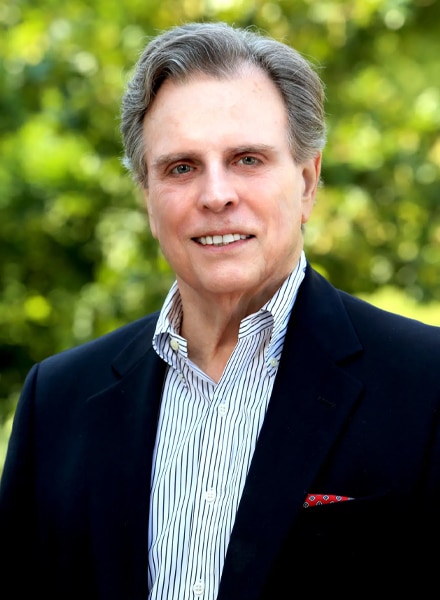 a man wearing a suit and tie smiling at the camera