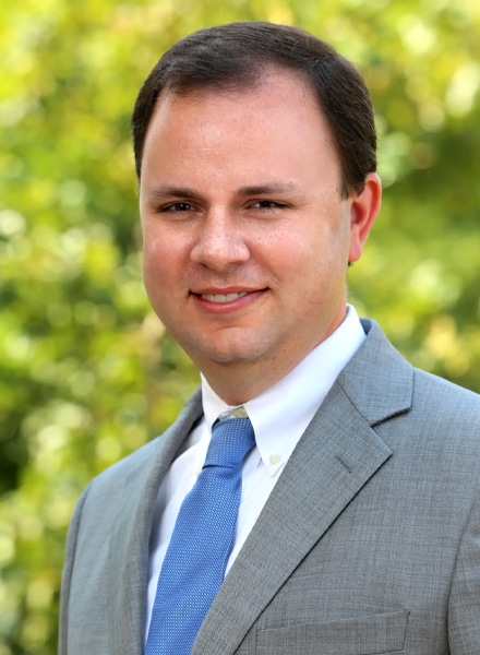 a man wearing a suit and tie smiling at the camera