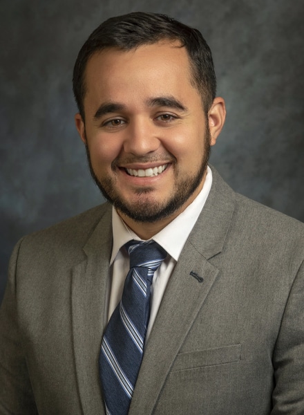 a man wearing a suit and tie smiling at the camera