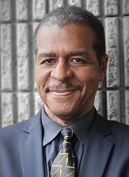 a man wearing a suit and tie smiling at the camera