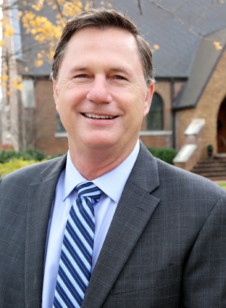 a man wearing a suit and tie smiling at the camera