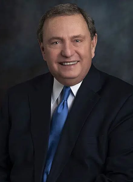 a man wearing a suit and tie smiling at the camera
