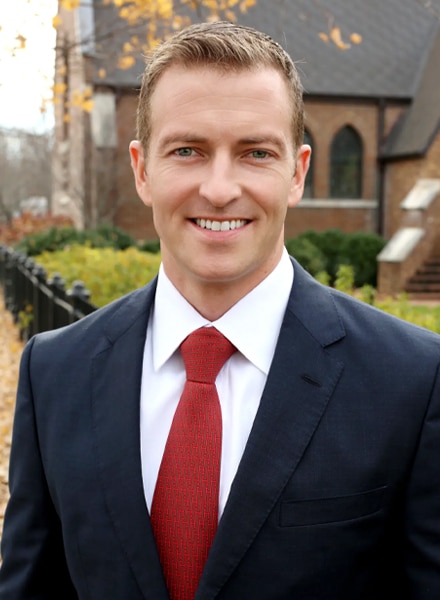 a man wearing a suit and tie smiling at the camera