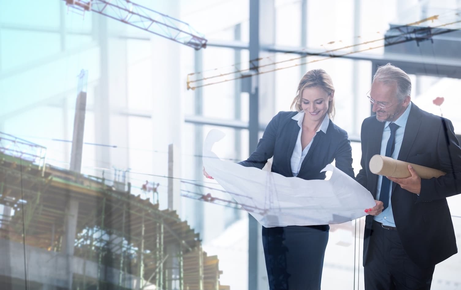 a person standing in front of a building showing another person architectural plans