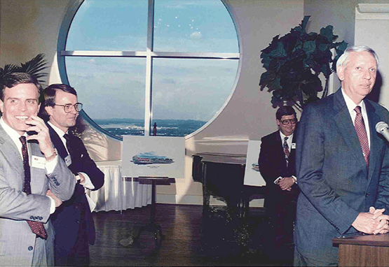 Photo taken in 1978 featuring four men at a podium with a large window in the backgroundat the announcement of Cooper & Grelier Becoming Part of NAI Global’s Original 10