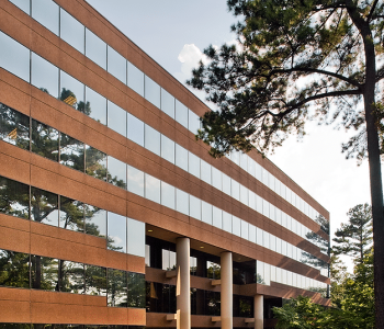 A Large Brick Building With Grass And Trees